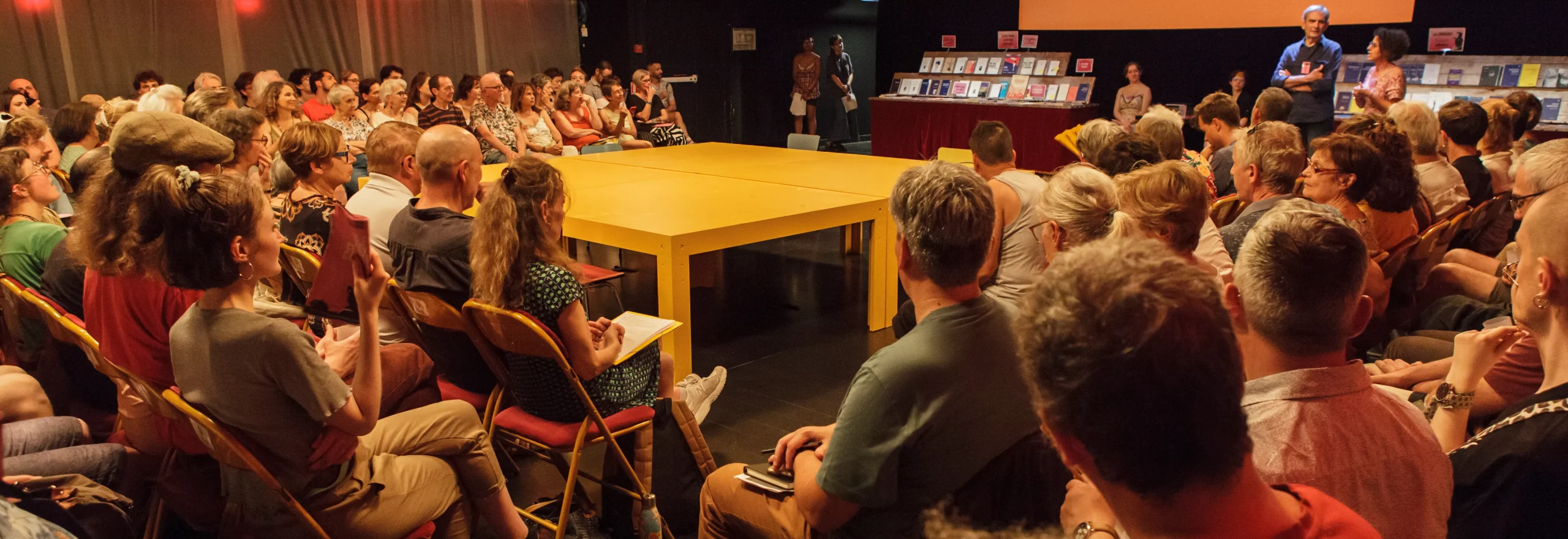 Le public autour de la table du festival avec la librairie en fond